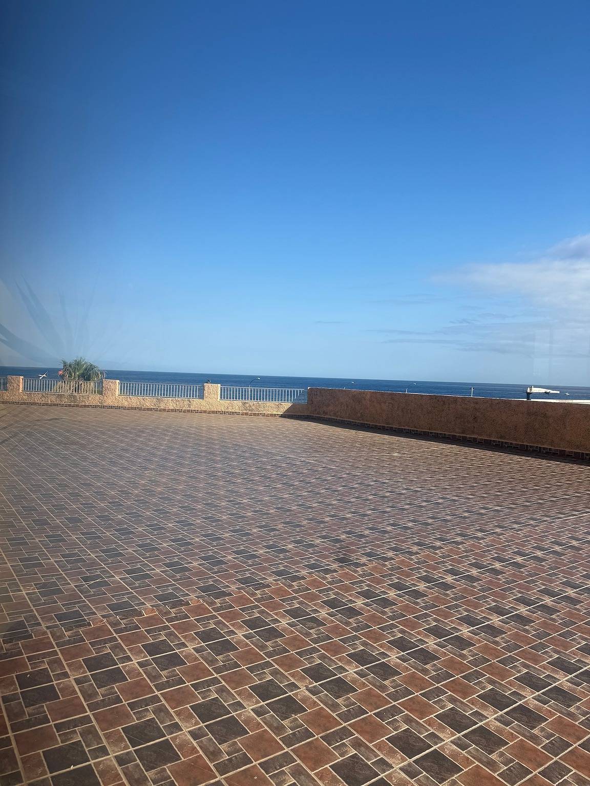 Tiled roof area of the building with the sea on the horizon